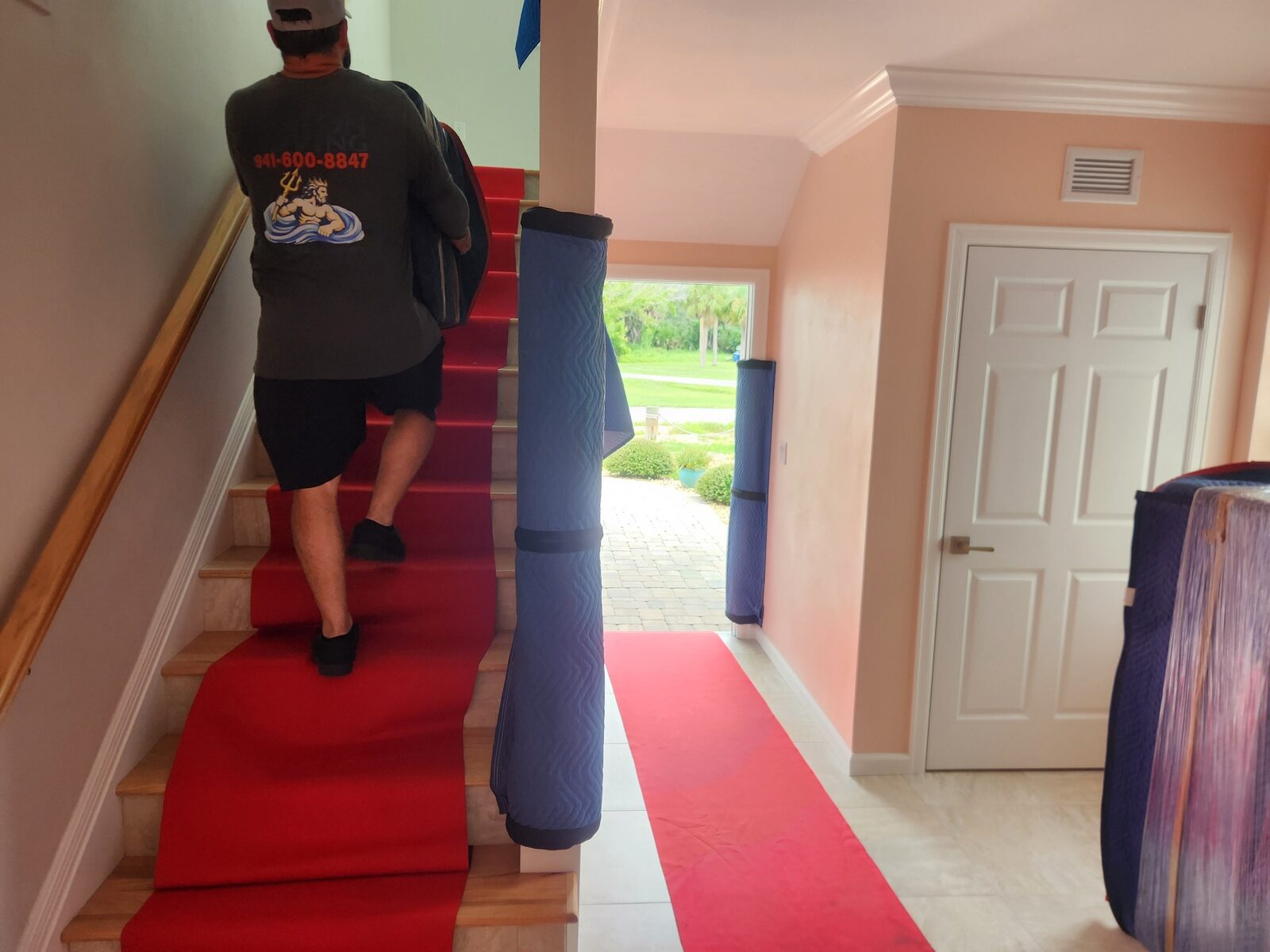 Mover carrying protected furniture on a fully covered stairway